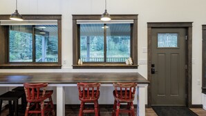 Une cuisine dotée d’un plan de travail en bois, de trois chaises en bois rouges et de deux lampes suspendues.