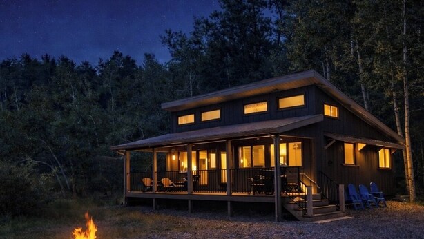 Une cabane dotée d’un porche couvert, d’un foyer et offrant une vue sur la forêt.