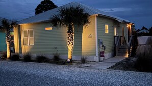 A single-story house with a gravel driveway, a palm tree, and a porch with steps leading to the front door. - Beach Cottage/2 pools/Golf Cart Friendly/Beach Access (Gulf Shores)