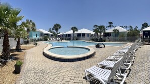 A pool area with lounge chairs, a hot tub, and palm trees. - Beach Cottage/2 pools/Golf Cart Friendly/Beach Access (Gulf Shores)