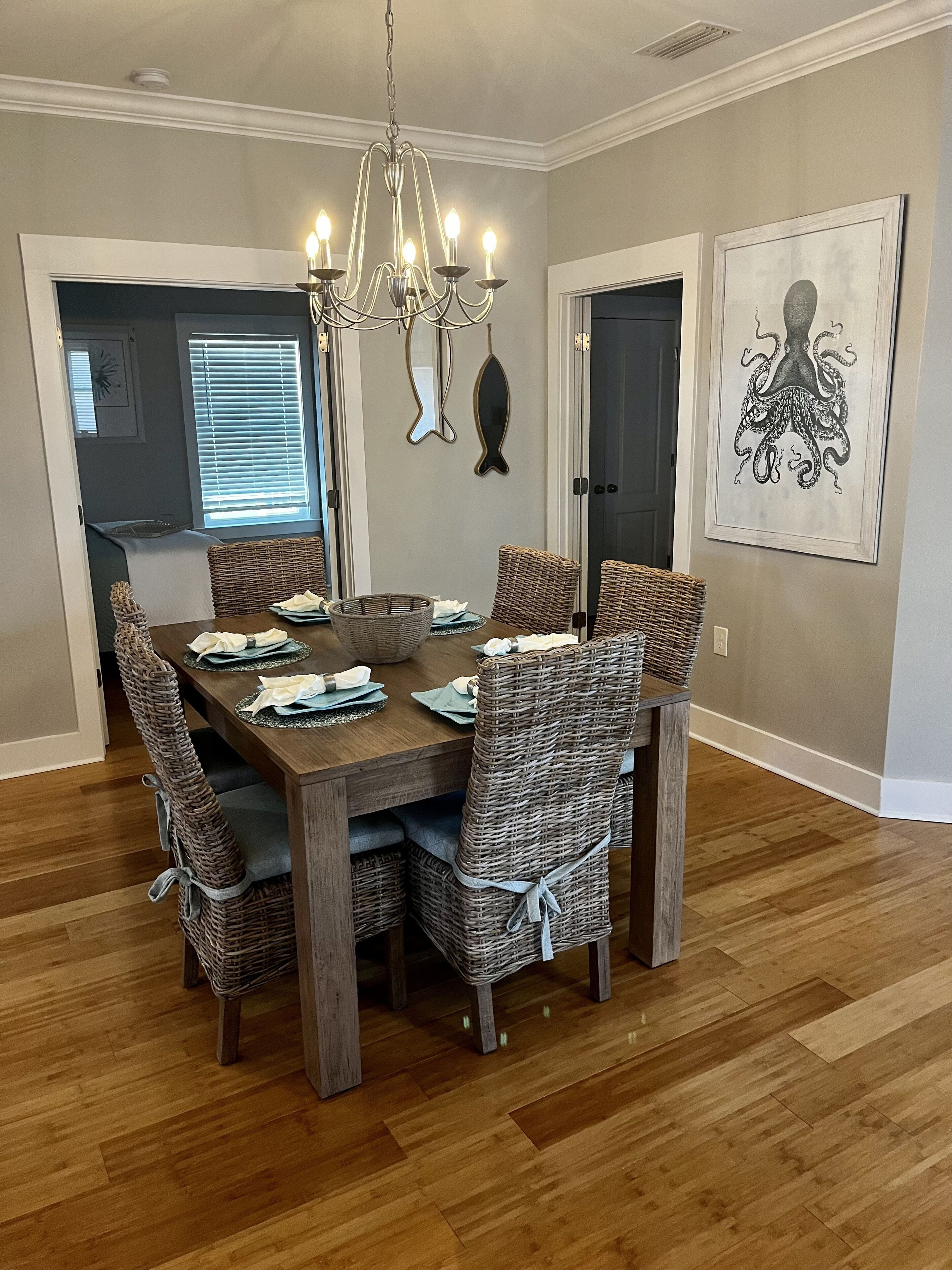 A dining room with a wooden table, wicker chairs, and a chandelier.