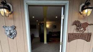 A wooden door with a welcome sign, a horse decoration, and a doormat with "WELCOME" on it.