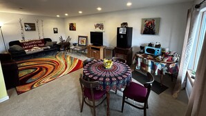 A living room with a sofa, a coffee table, and a TV. There is a patterned rug on the floor.