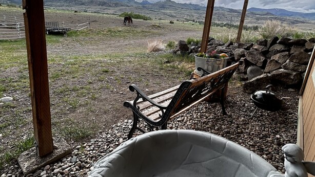 A rustic outdoor seating area with a stone table and bench, overlooking a mountainous landscape.