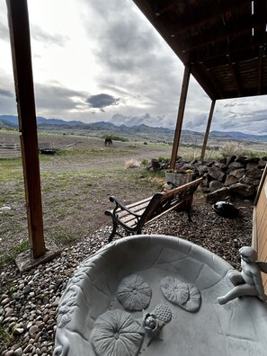 A rustic outdoor seating area with a stone table and bench, overlooking a mountainous landscape.