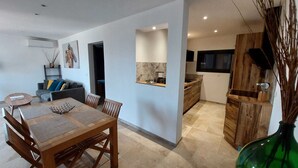 Una cocina moderna con armarios de madera, un comedor con mesa y sillas de madera, y una sala de estar con un sofá y elementos decorativos.
