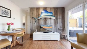 A dining area with a wooden table and chairs, a white cabinet, and a large fish mural on the wall.