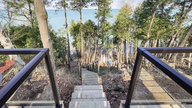 A wooden staircase leading down to a beach, surrounded by trees and a railing.