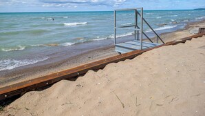 A beach with a metal lifeguard stand and a wooden walkway. - Sunset at SchadeView, Lake views, King Bed (Dashwood)
