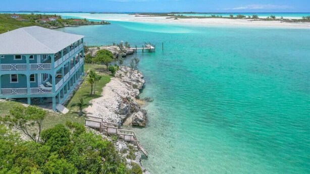 Un immeuble à plusieurs étages doté de balcons donnant sur des eaux turquoise et un ciel dégagé.
