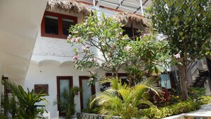 A courtyard with a thatched-roof structure, potted plants, and outdoor seating.