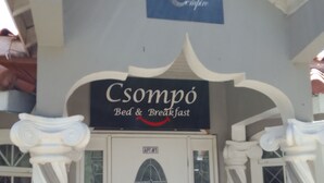 A building entrance with a sign reading "Csompo Bed & Breakfast" and a door labeled "APT #1". - The cloud room At Csompo Silver Manor (Tower Isle)
