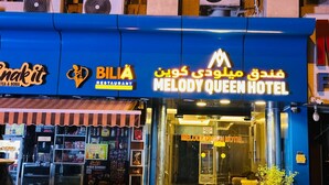 Un hotel con fachada azul, un restaurante llamado 'Bilia' y una tienda llamada 'Snakit'.