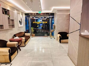 A modern lobby with a reception desk, seating area, and a view of the street outside.