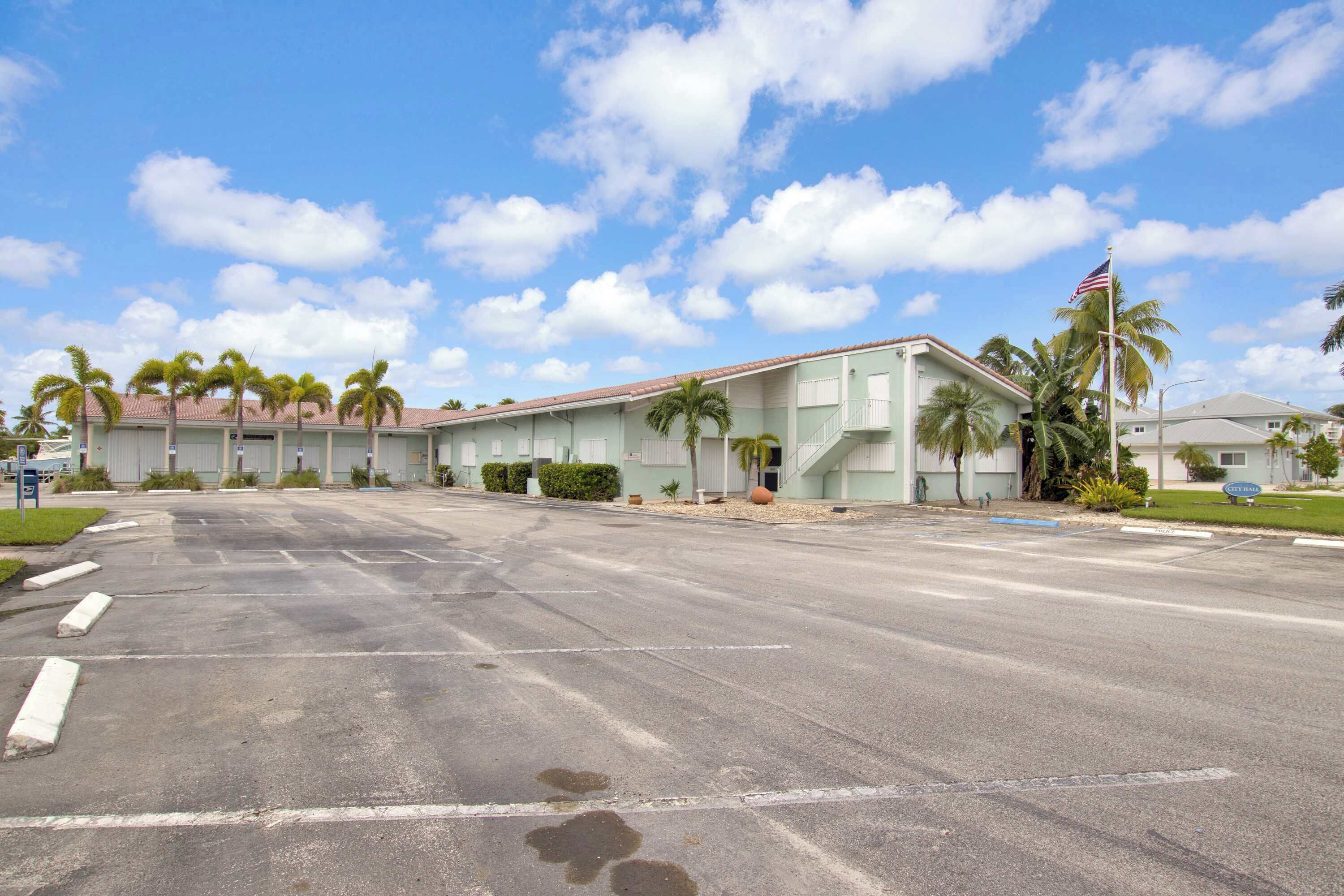 A motel with a row of rooms, a parking lot, and a palm tree.