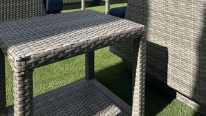 An outdoor seating area with wicker furniture and a modern building in the background.
