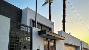 A modern building with a large window, a door with a decorative screen, and a garage door.
