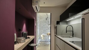 Una cocina moderna con un lavamanos integrado, una cafetera y un comedor con una mesa y sillas blancas.