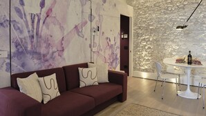 Una sala de estar moderna con un sofá rojo, una mesa de comedor blanca y una pared de piedra.
