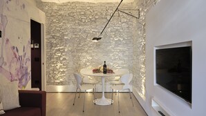 Un comedor moderno con pared de piedra, una mesa redonda y sillas blancas.