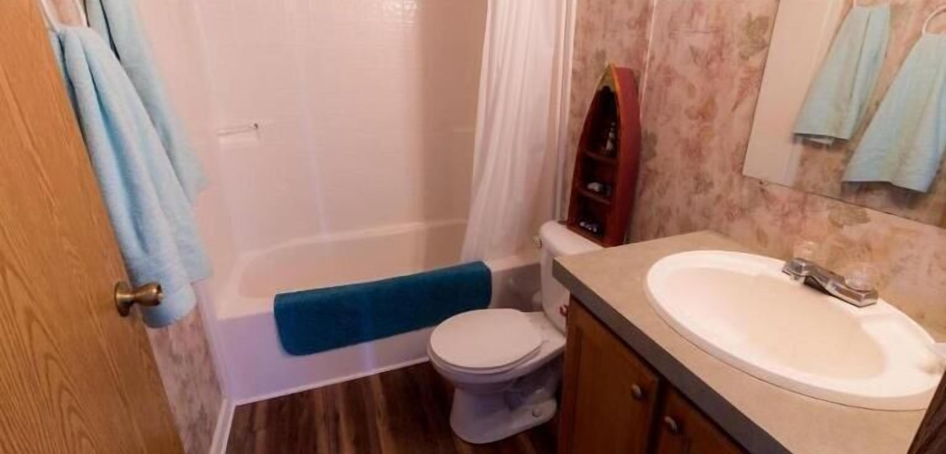 A bathroom with a white toilet, a sink, a blue towel, and a shower curtain.