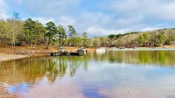 Un lago tranquilo con muelles y barcos, rodeado de árboles y un cielo despejado.