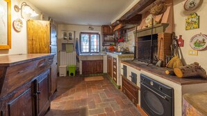 Une cuisine rustique avec des meubles en bois, un poêle d’époque et un four en briques.