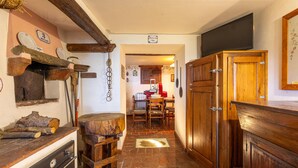 Une cuisine rustique avec des poutres en bois, un sol en pierre et une table en bois entourée de tabourets.