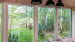 Una habitación con ventanas amplias que dan a un jardín exuberante y árboles.