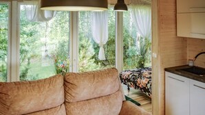 Una habitación acogedora con sofá, una mesa de comedor y vistas a la vegetación exterior.