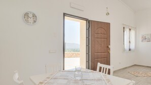 A dining area with a table set for two, a wooden door, and a view of the outdoors. - Cozy home in Floridia (Floridia)
