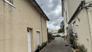 A narrow street with buildings on either side, featuring a mix of residential and commercial properties. - Oasis Urbain (Argenteuil)