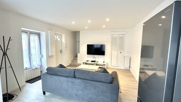 A modern living room with a grey sofa, a flat-screen TV, and a large window. - Oasis Urbain (Argenteuil)