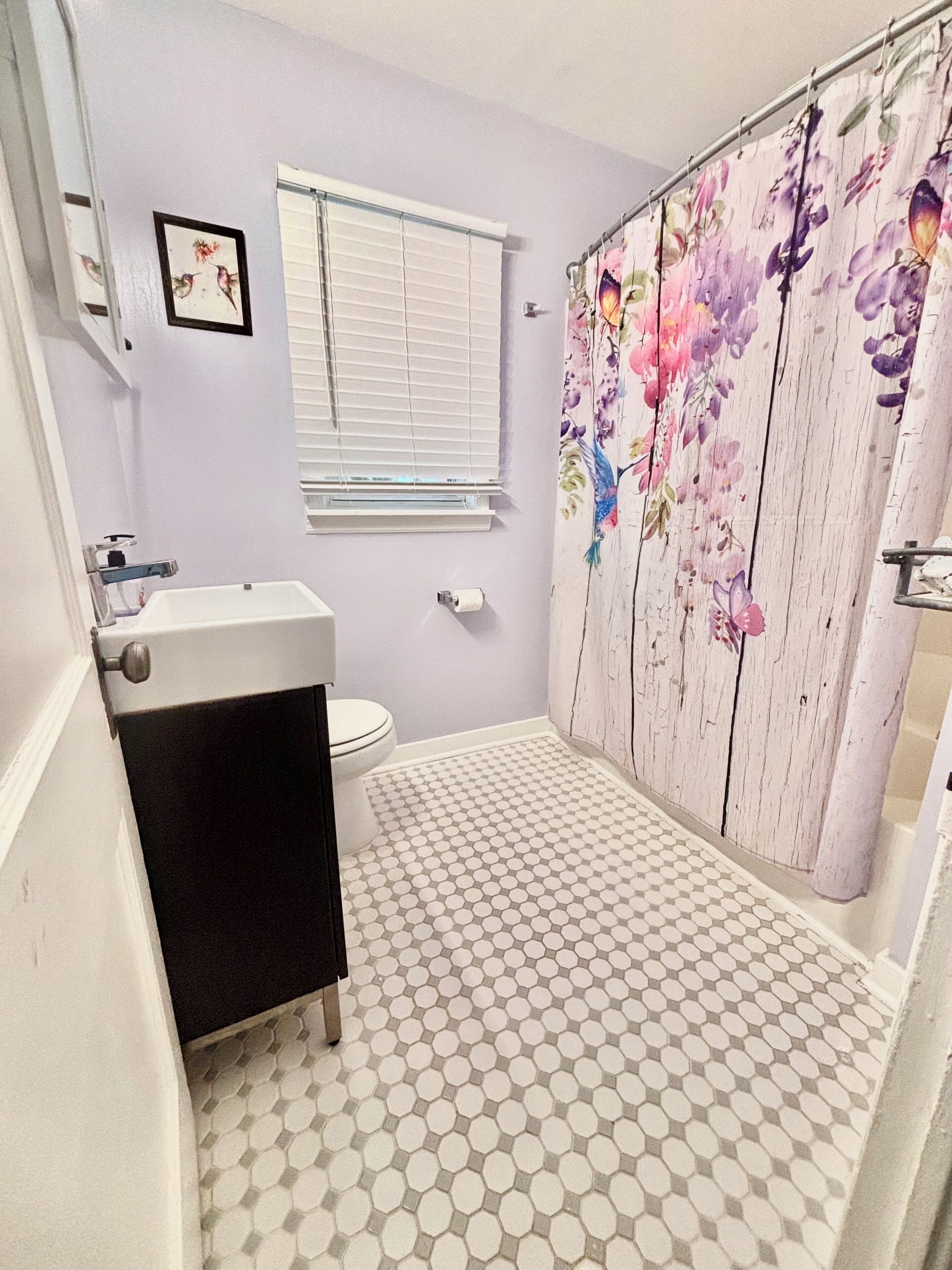 A bathroom with a toilet, sink, and shower curtain.