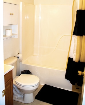 Une salle de bain équipée de toilettes, d’une baignoire et d’un rideau de douche.