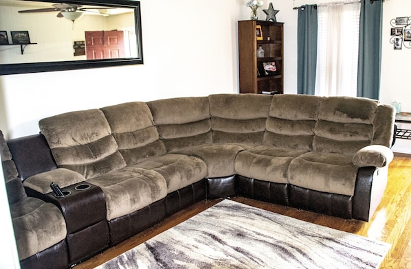 A sectional sofa with a built-in side table, a wooden floor, and a patterned rug.