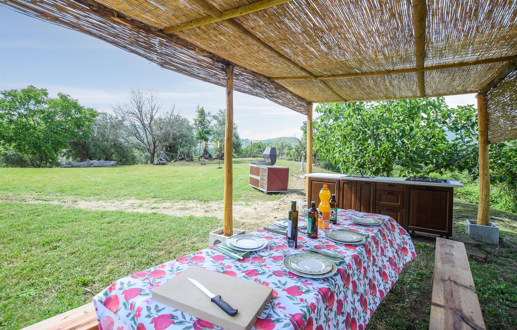 Un área de comedor al aire libre con una mesa para cuatro, una parrilla y un armario de madera.