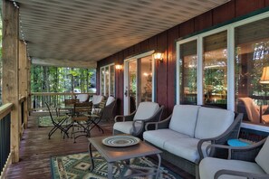Un espace extérieur aménagé, abrité et doté de mobilier en osier, d’une table et offrant une vue sur la verdure environnante.