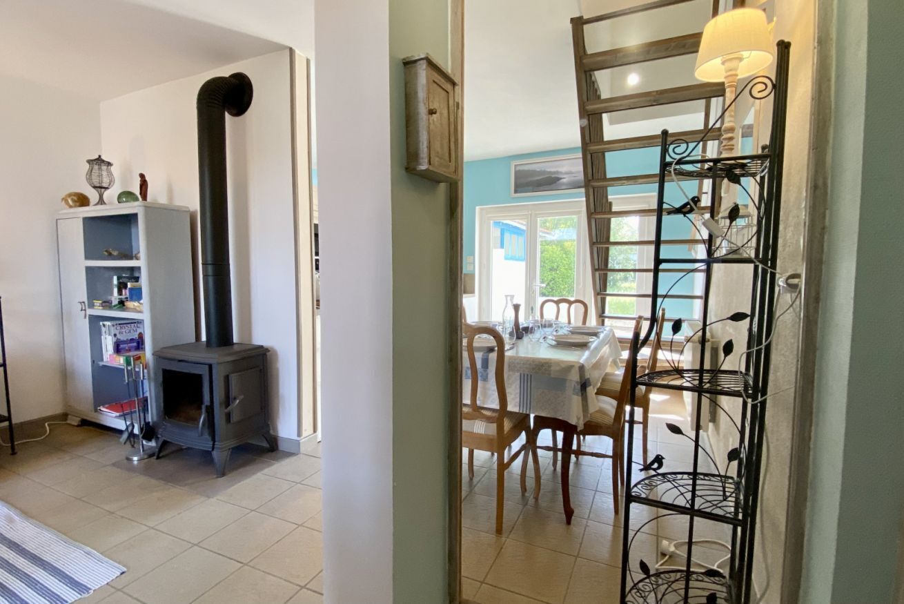 A room with a fireplace, a dining table with chairs, and a metal rack with decorative items.