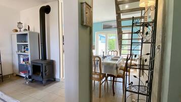 A room with a fireplace, a dining table with chairs, and a metal rack with decorative items.
