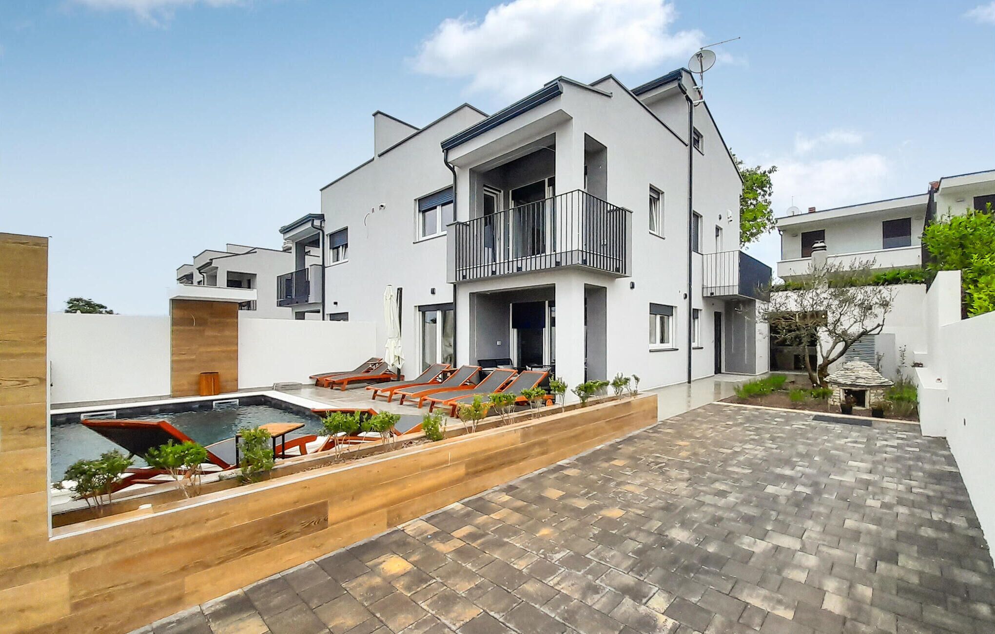 Et moderne hus med to etager, swimmingpool, udendørs møbler og en velplejet have.