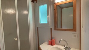 Un baño con techo de madera, un lavamanos blanco, un espejo y una puerta.