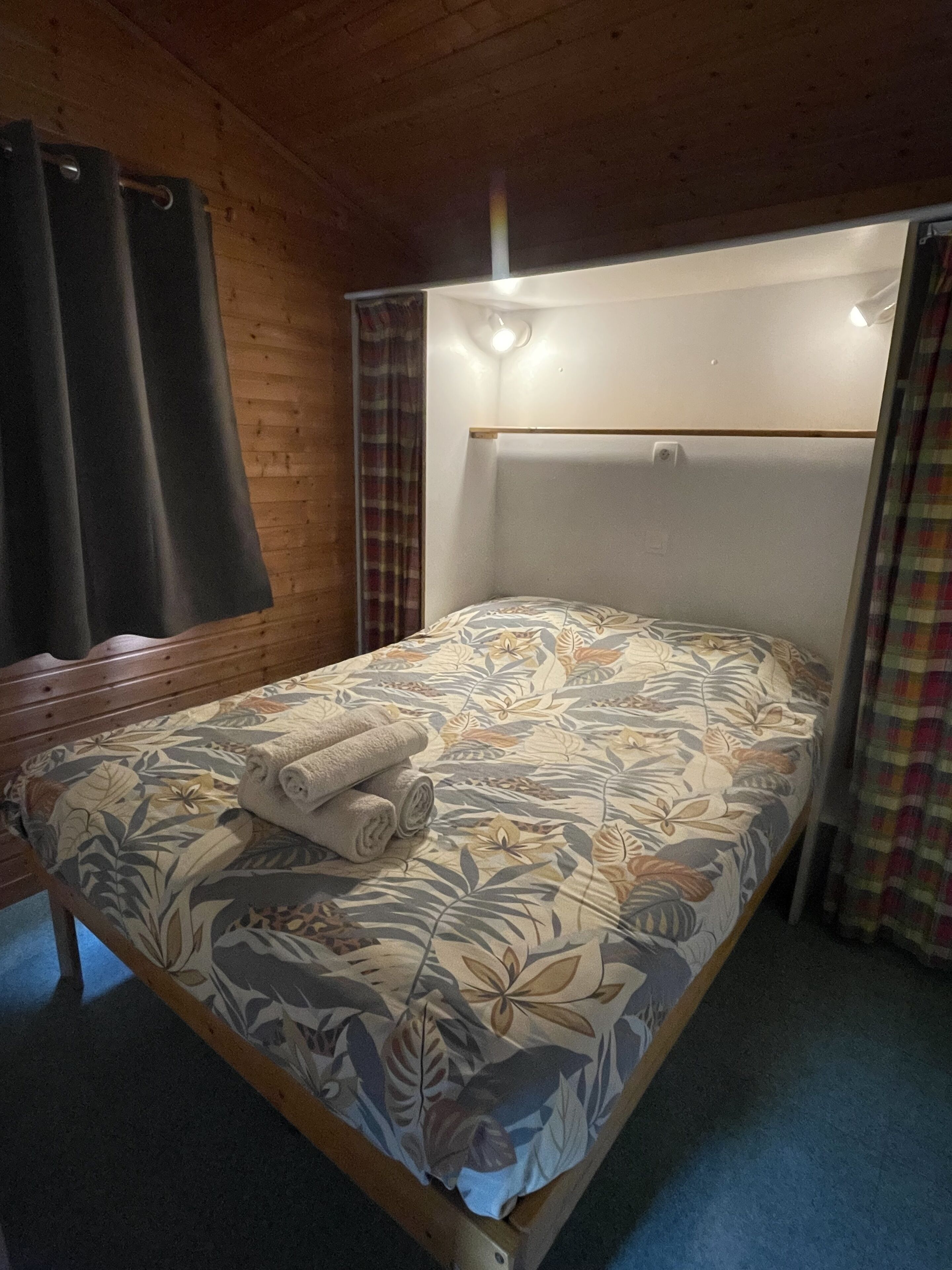Una cama individual con una colcha estampada de flores, un cabecero de madera y una lámpara de noche.