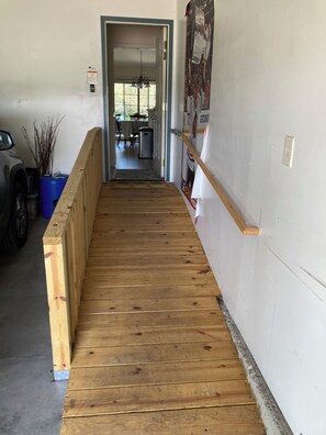 A wooden staircase leading to a room with a door, a blue container, and a vehicle parked outside.