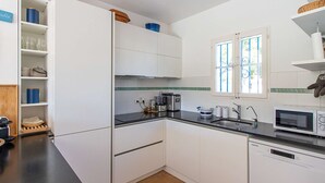 A compact kitchen with white cabinets, a black countertop, a microwave, and a toaster. - PORT GRIMAUD Renovated South-oriented house - A/C, WIFI, 11m mooring (Grimaud)