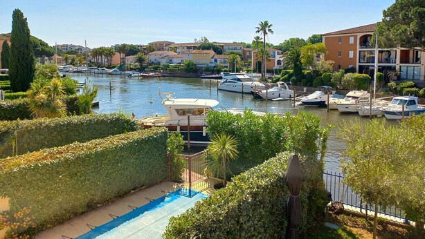 A marina with boats docked, a swimming pool, and residential buildings in the background. - PORT GRIMAUD Renovated South-oriented house - A/C, WIFI, 11m mooring (Grimaud)
