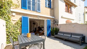 An outdoor patio with a table and chairs, a sofa, and a bicycle. - PORT GRIMAUD Renovated South-oriented house - A/C, WIFI, 11m mooring (Grimaud)