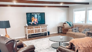 Una sala de estar con televisor, sofás de cuero, una mesa de centro y un tapete estampado.