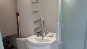 A bathroom with a toilet, sink, and shower. - Studio lumineux proche de la mer (Saint-Nazaire)