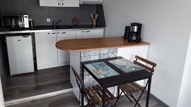 A compact kitchen with white cabinets, a wooden countertop, and a coffee maker. There is a small refrigerator and a tiled backsplash. - Studio lumineux proche de la mer (Saint-Nazaire)